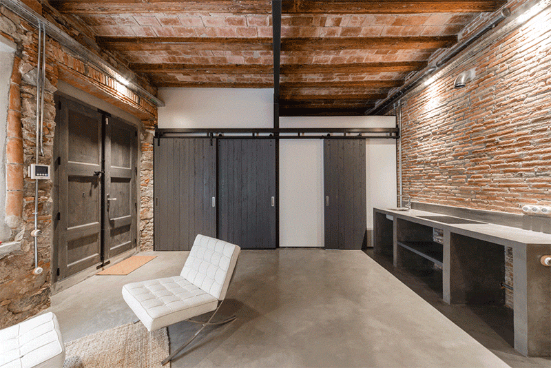 In this renovated workshop, barn doors can expose or close off the bedroom and the bathroom from the rest of the space.
