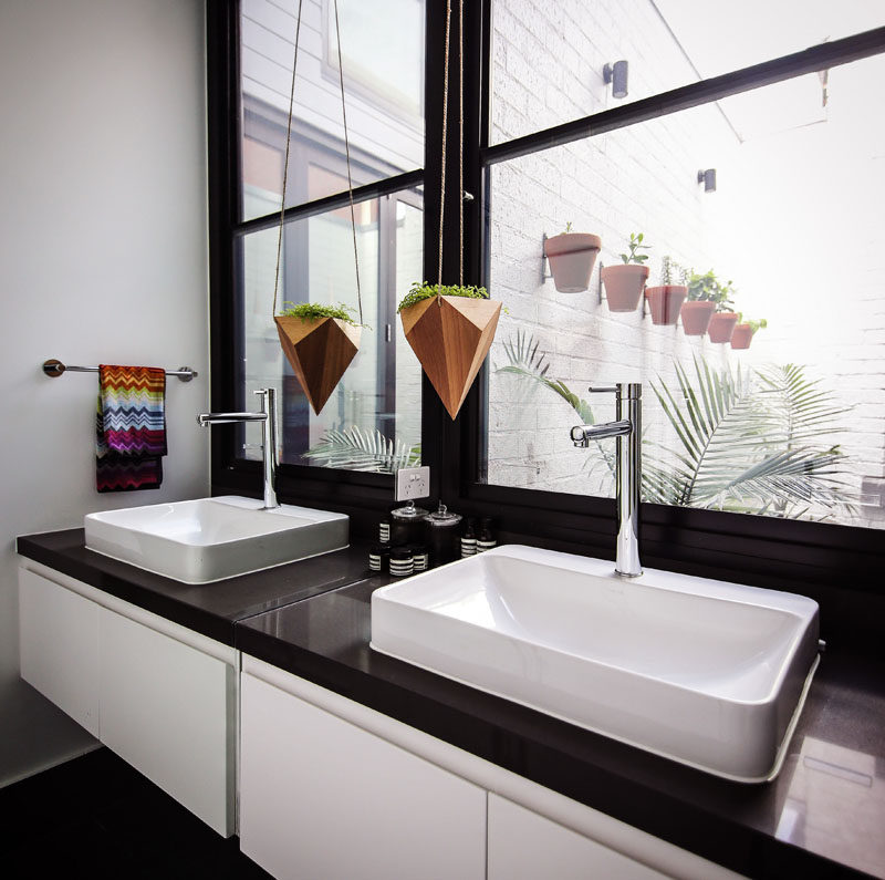 In this black and white bathroom, there's windows providing lots of natural light and views of a small courtyard.