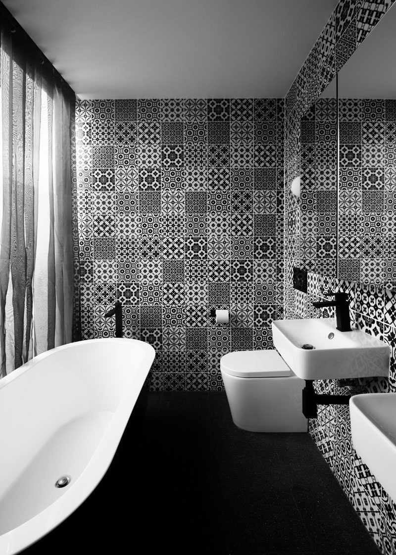 In this black and white bathroom, decorative tiles help to keep the space fun and a large mirror helps to reflect light throughout.
