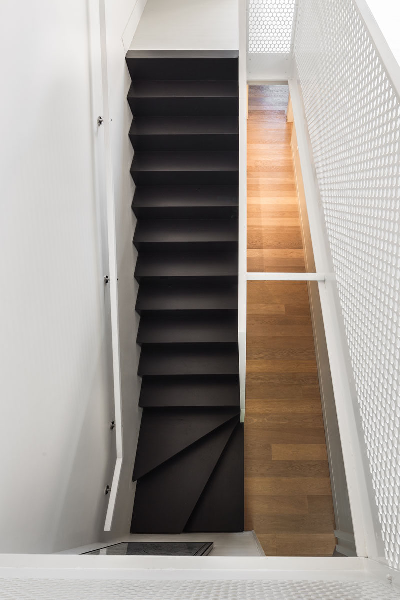 Dark stairs strongly contrast the light wood floors and white walls in this renovated home.