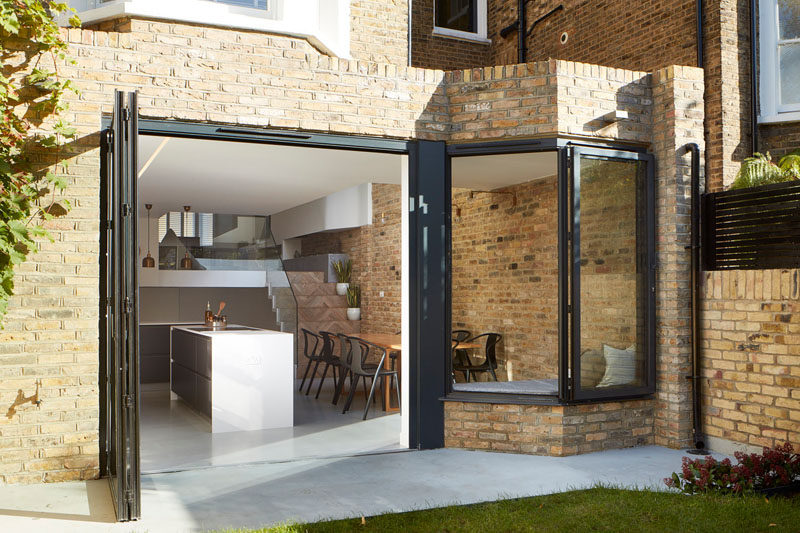 In this renovated british home, large folding doors and a window all open up to the backyard, ideal for indoor/outdoor living.