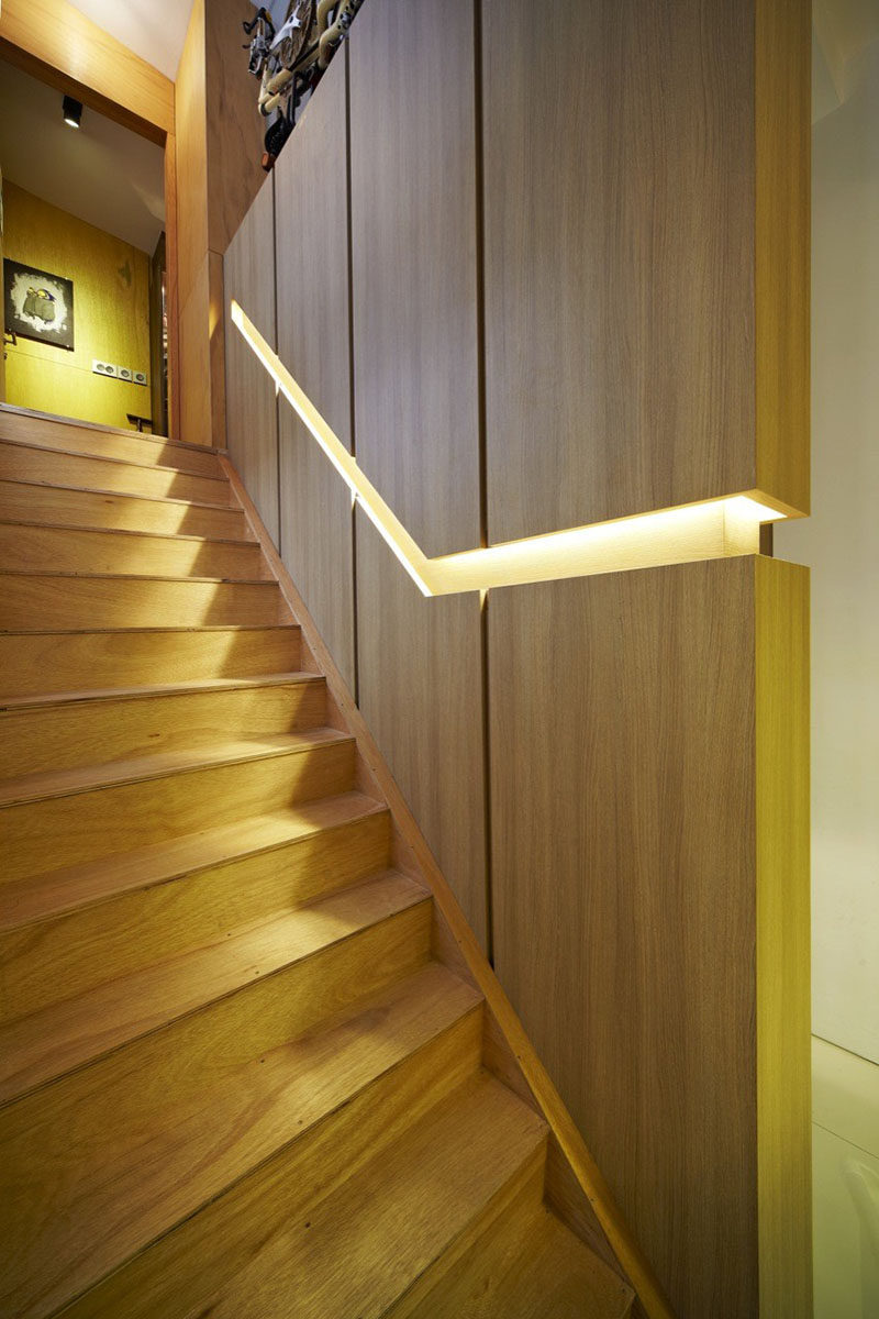 Stair Design Idea - 9 Examples Of Built-In Handrails // In this Singaporean home, a wooden wall is broken up by the built-in handrail that features hidden lighting.