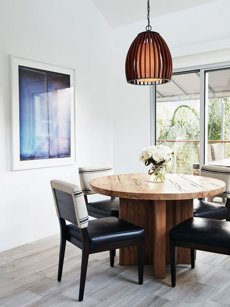 A circular wooden dining table and singular pendant light makes for an intimate dining experience.