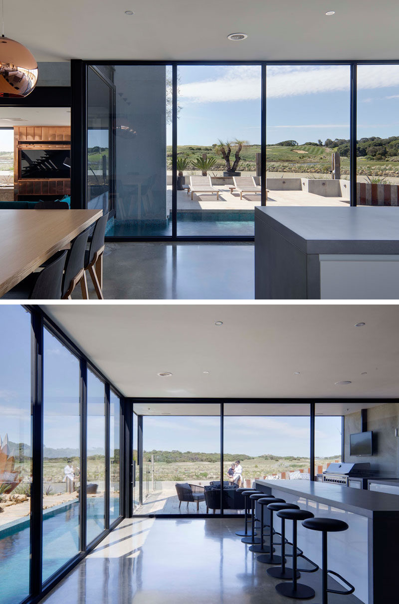 Floor-to-ceiling windows with black frames that surround the living, dining and kitchen areas provide views of the swimming pool and golf course.