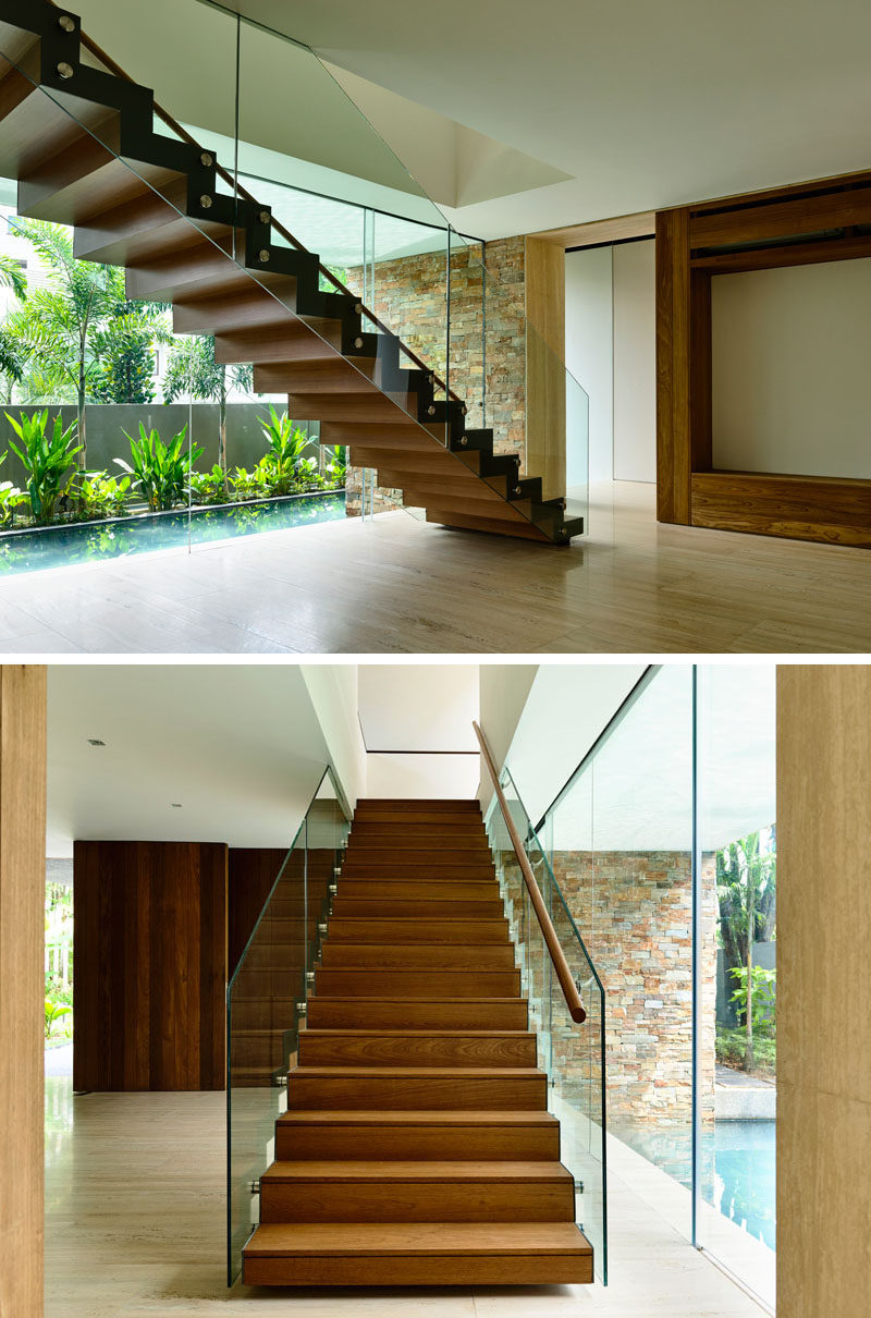 This Singaporean home has wooden stairs with a glass railing.