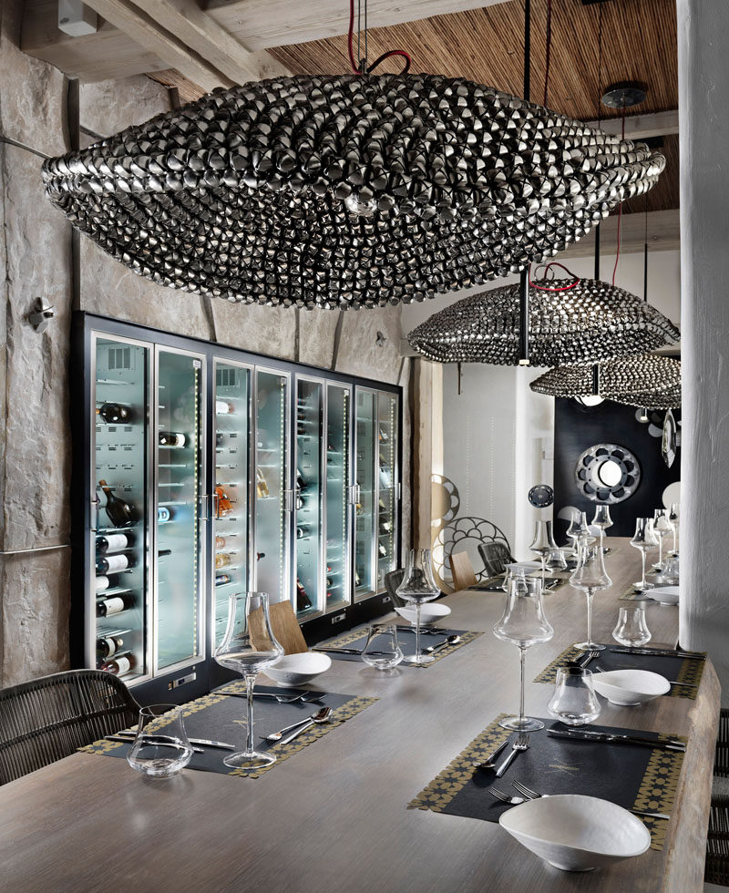 Large sculptural pendant lights hang above these restaurant tables, while a large wine fridge sits flush with the wall.