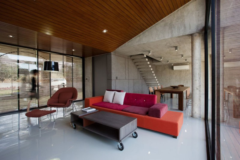Wood and brightly colored furniture soften up the interior of this concrete home.