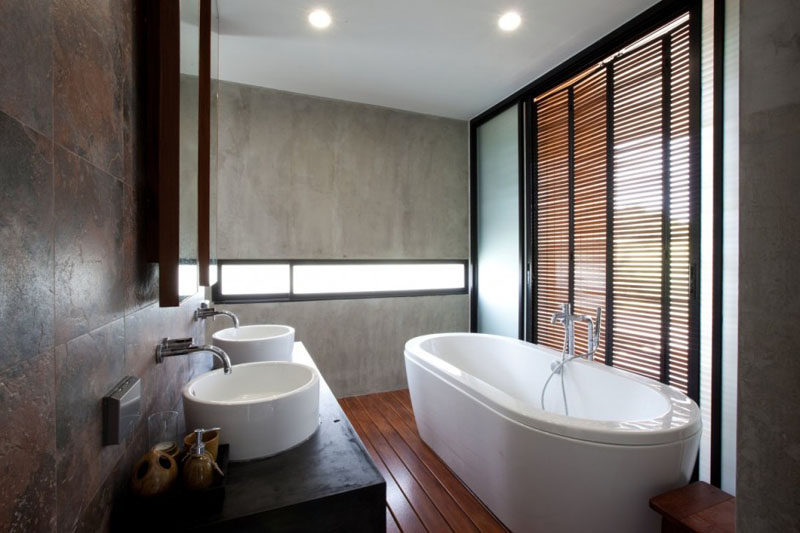 In this master bathroom, a letterbox window gives a glimpse of the outdoors and wooden shutters provide privacy but also let fresh air through.