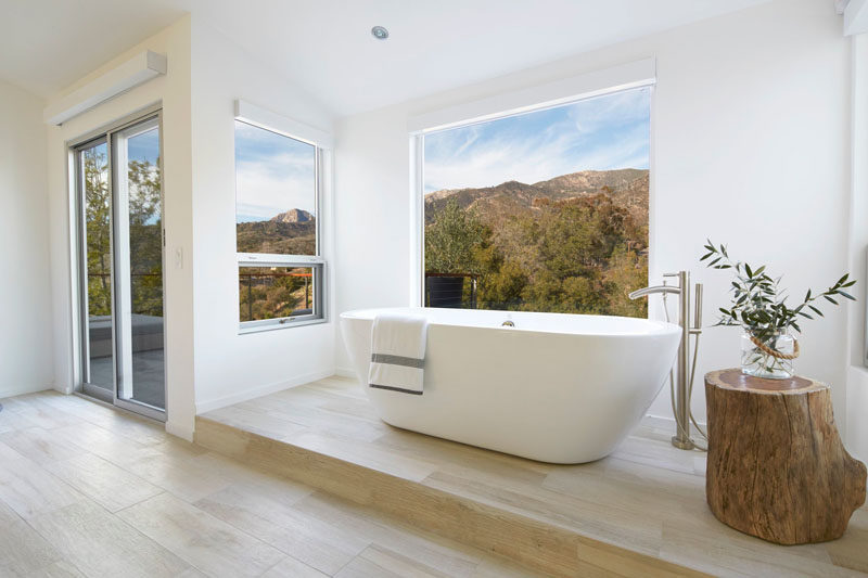 This master bathroom features a freestanding bathtub raised up onto a platform so that whoever is in the bath can easily enjoy the picturesque views of the surrounding landscape.