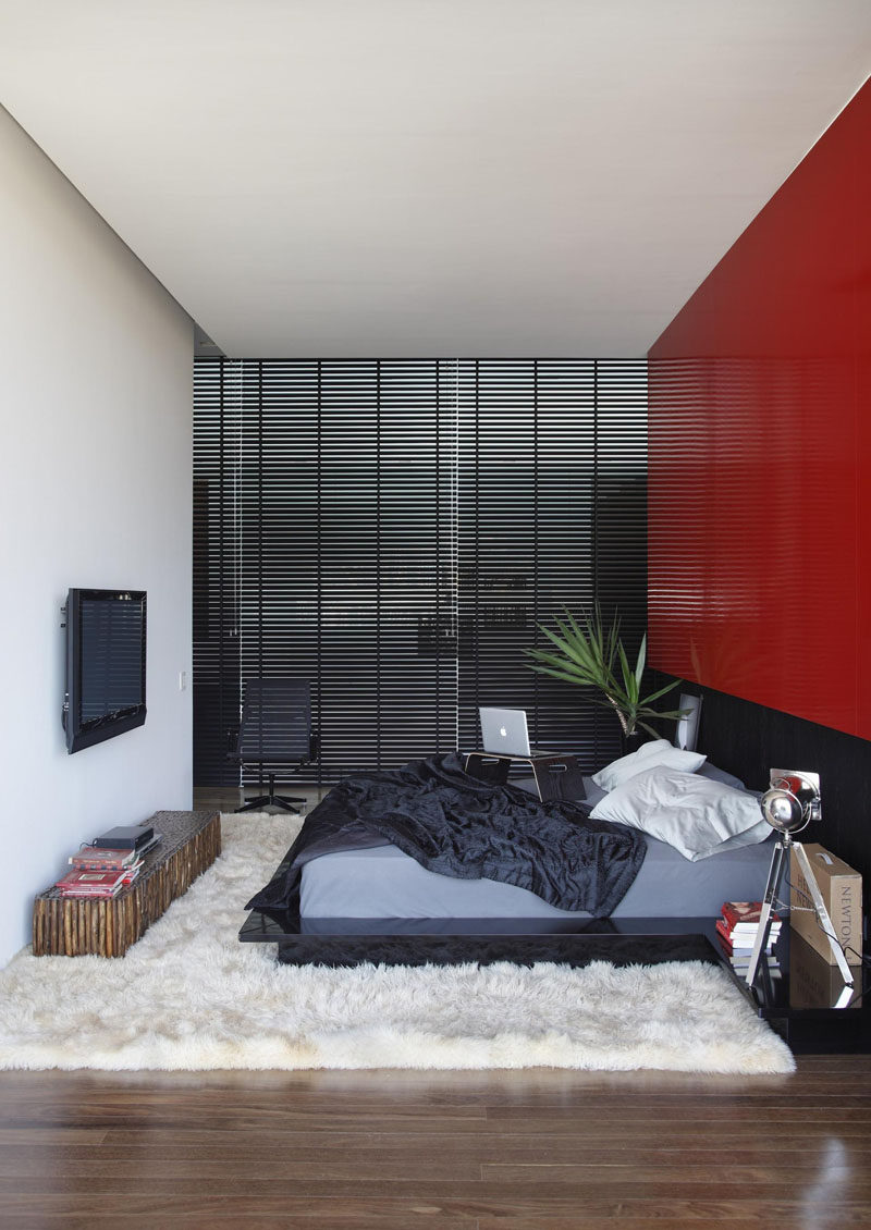 A bright red feature wall stands out in this otherwise black and white bedroom.