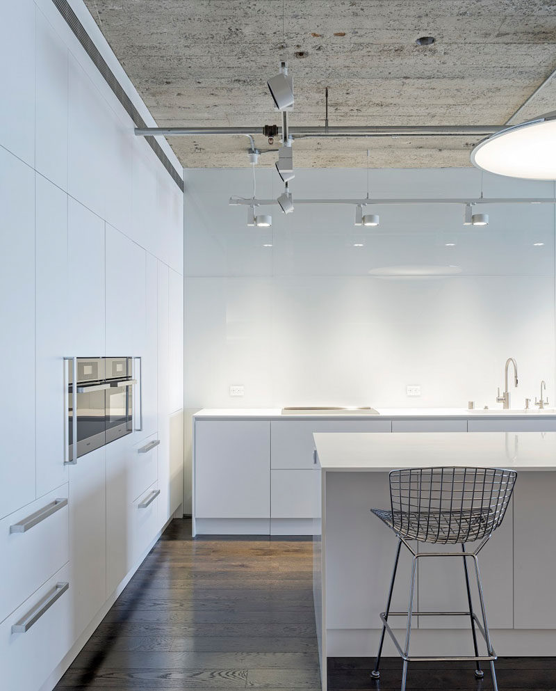 Kitchen Design Ideas - White, Modern and Minimalist Cabinets // The walls of white cabinetry contrast the concrete in this apartment and makes for a minimalist feel throughout.