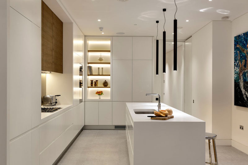 Kitchen Design Ideas - White, Modern and Minimalist Cabinets // Warm wood above the stove, and soft lighting creates a cozier feel in this kitchen with all white cabinetry.