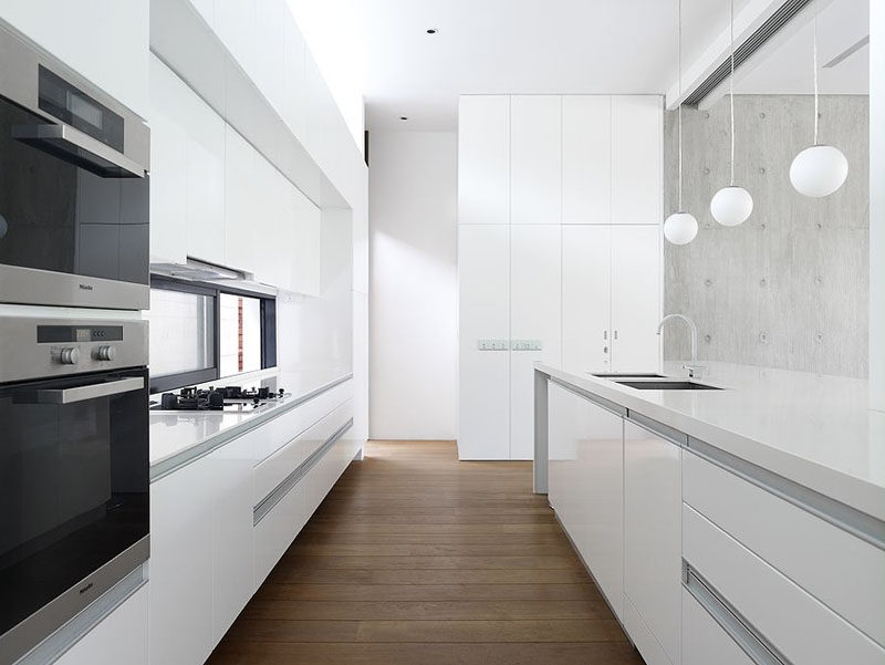 Kitchen Design Ideas - White, Modern and Minimalist Cabinets // The hardware-free white cabinets of this kitchen are softened up by warm wood flooring.