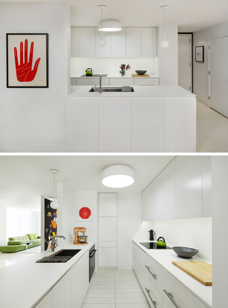 Kitchen Design Ideas - White, Modern and Minimalist Cabinets // The white cabinetry in this kitchen is only broken up by the black appliances and small decorative elements like the green kettle and red art piece.