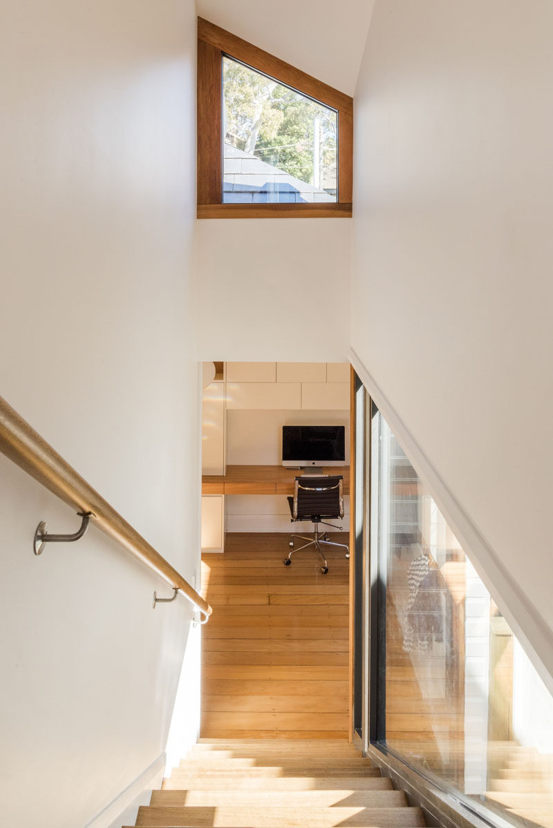 These wooden stairs, handrail and window frames break up white walls and ceiling.