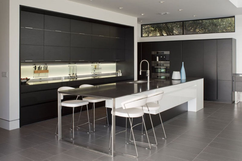 The design of this kitchen has been kept minimal, with black cabinetry and a long island with space for informal dining.