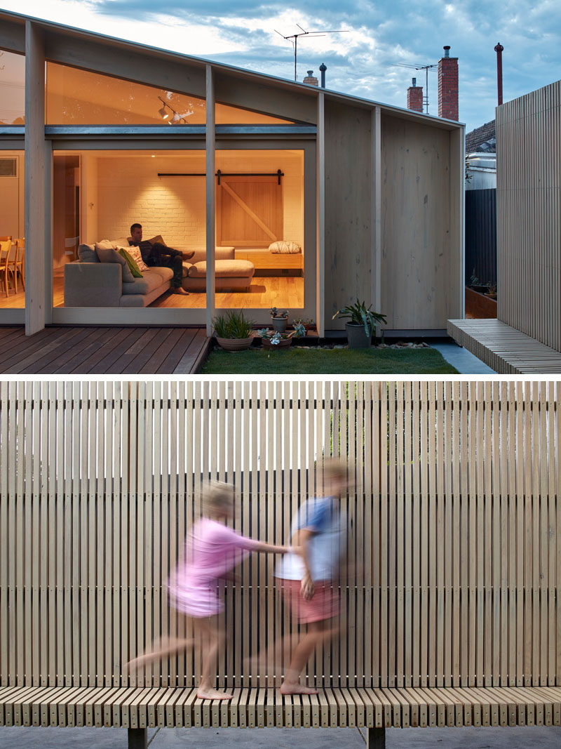 A wooden deck has been added to the back of this renovated house, and along one side of the yard is a wooden slat bench that also provides seating and privacy from the neighbors.