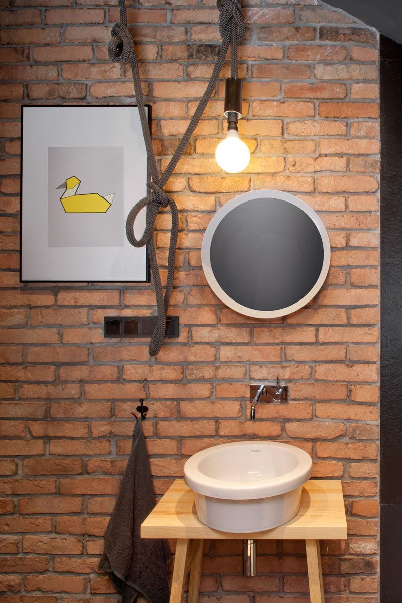 In this guest bathroom, a brick feature wall has been paired with a light hanging from a rope for a more industrial look.