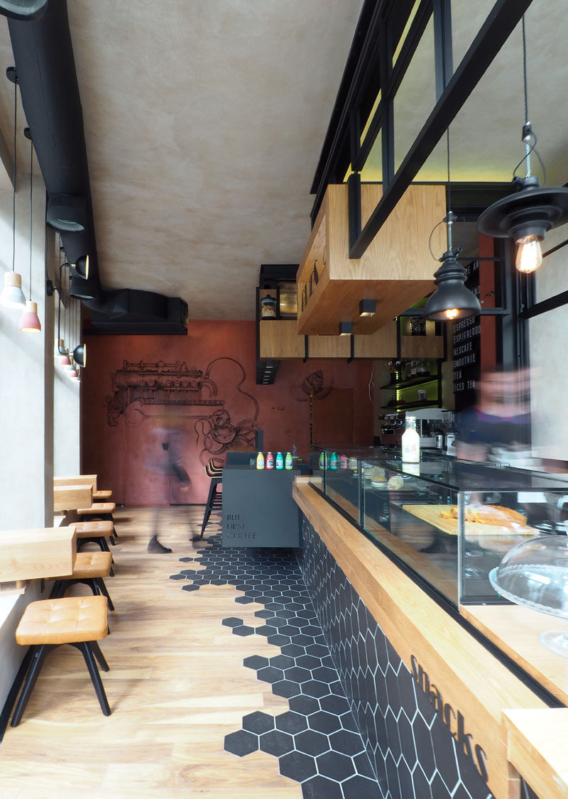 This modern coffee shop has black hexagon tiles that wrap around from the counter down to the laminate wood flooring.