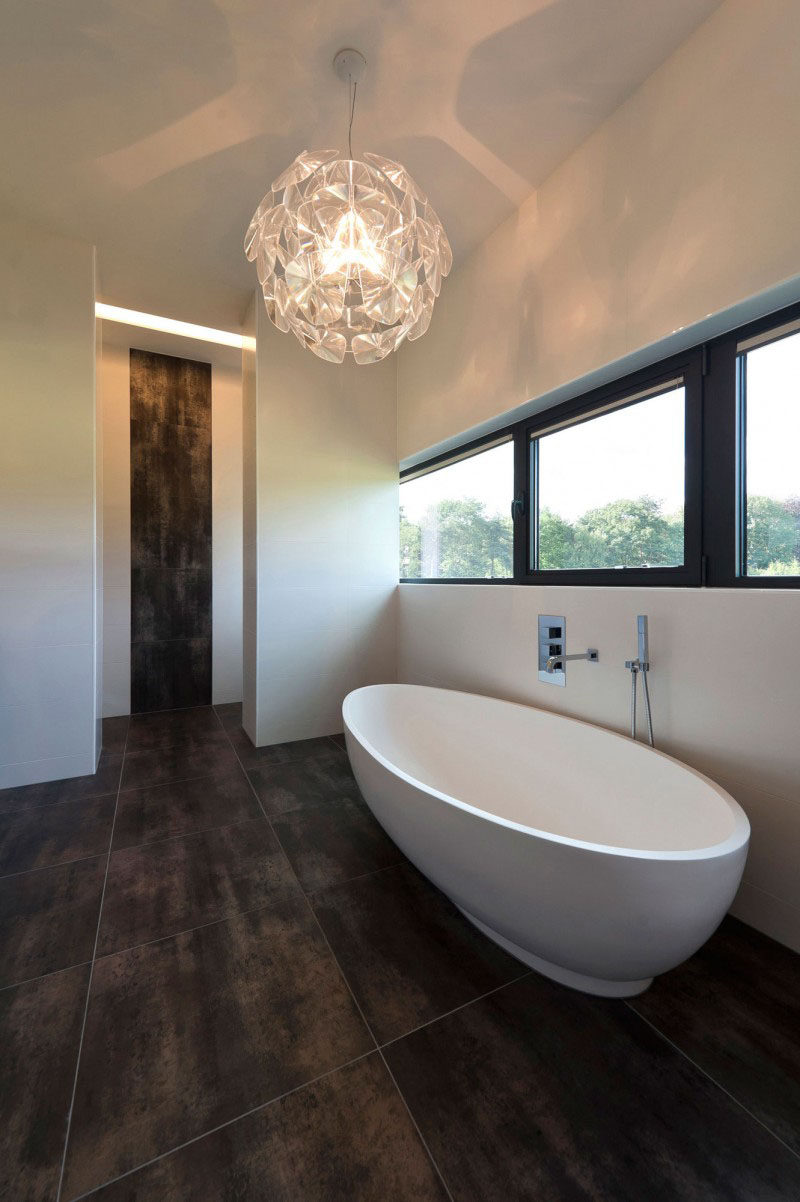 Bathroom Tile Ideas - Use Large Tiles On The Floor And Walls // The large dark tiles in this bathroom allow this bathroom to feel extra lavish, and the continuation of the tile up part of the wall just outside the bathroom makes the space feel connected to the rest of the house.