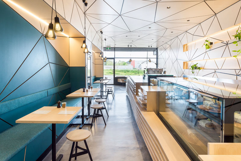 In this modern cafe, a long L-shaped service counter kinks and bends along its length, and the floor is made from concrete resin as it's a practical and hard-wearing material.