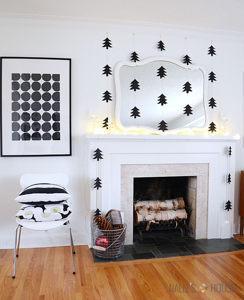 30 Modern Christmas Decor Ideas For Your Home // Black paper tree cut outs hanging from the ceiling frame the fireplace and make the room feel more cozy.