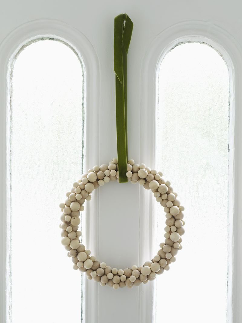 21 Modern Wreaths To Decorate Your Home With This Holiday Season // Gluing wood beads to a wreath form is an easy way to create a Nordic looking wreath that can either be left with its natural finish or painted festive colors.