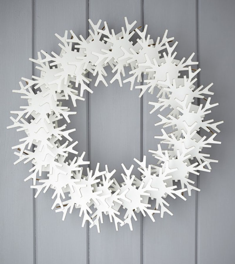 21 Modern Wreaths To Decorate Your Home With This Holiday Season // This modern wreath featuring cardboard snowflakes creates a geometric looking wreath that's both festive and unique.