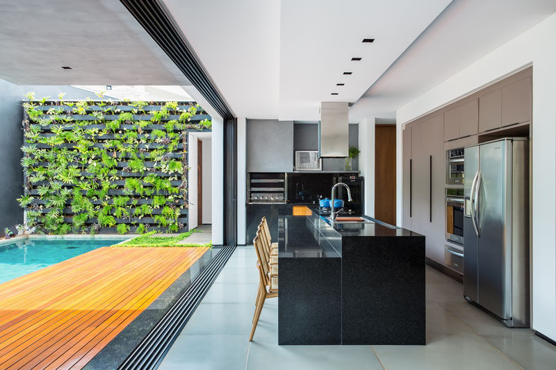 This gourmet kitchen, that opens to the backyard, has a central black island with a lower section that is the perfect height for a group of dining chairs.