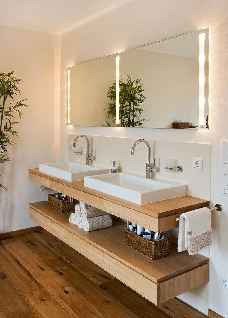 Bathroom Design Ideas - Open Shelf Below The Countertop // Dual sinks sit above a floating wooden shelf that's just the right height to store various lotions, potions, and creams as well as a stack of towels.