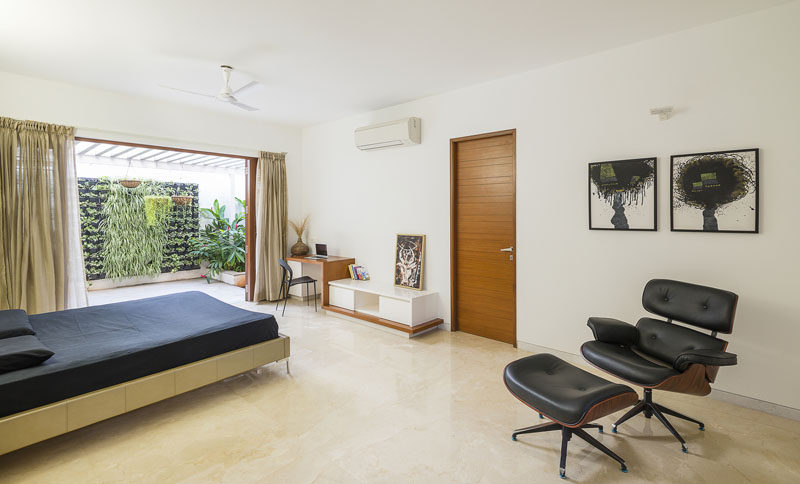 This spacious bedroom with built-in desk features a private balcony with a small green wall.