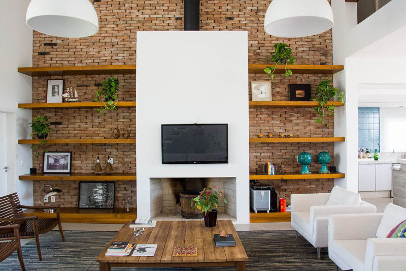 8 TV Wall Design Ideas For Your Living Room // A real fireplace sits beneath this TV that's also surrounded by storage to create a comfortable and practical living room.