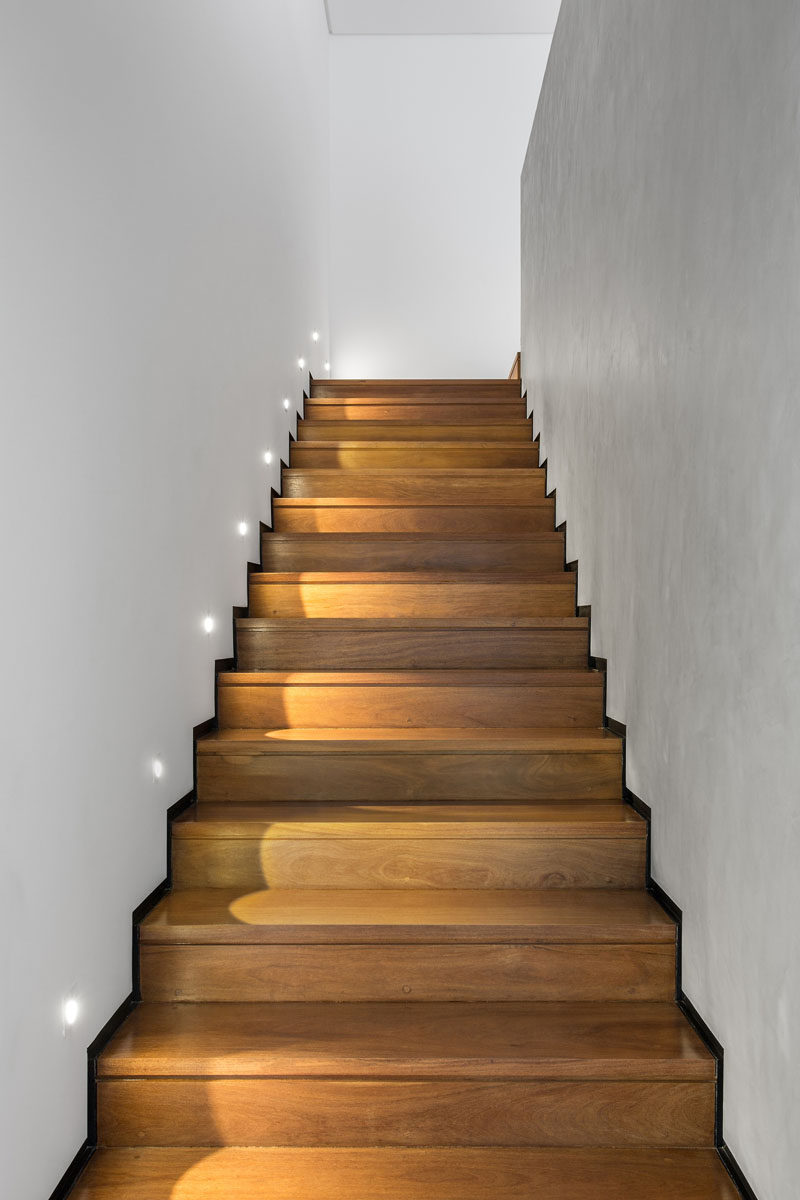 Wooden stairs with black metallic skirting boards and lighting, lead you to the upper floor of this home.