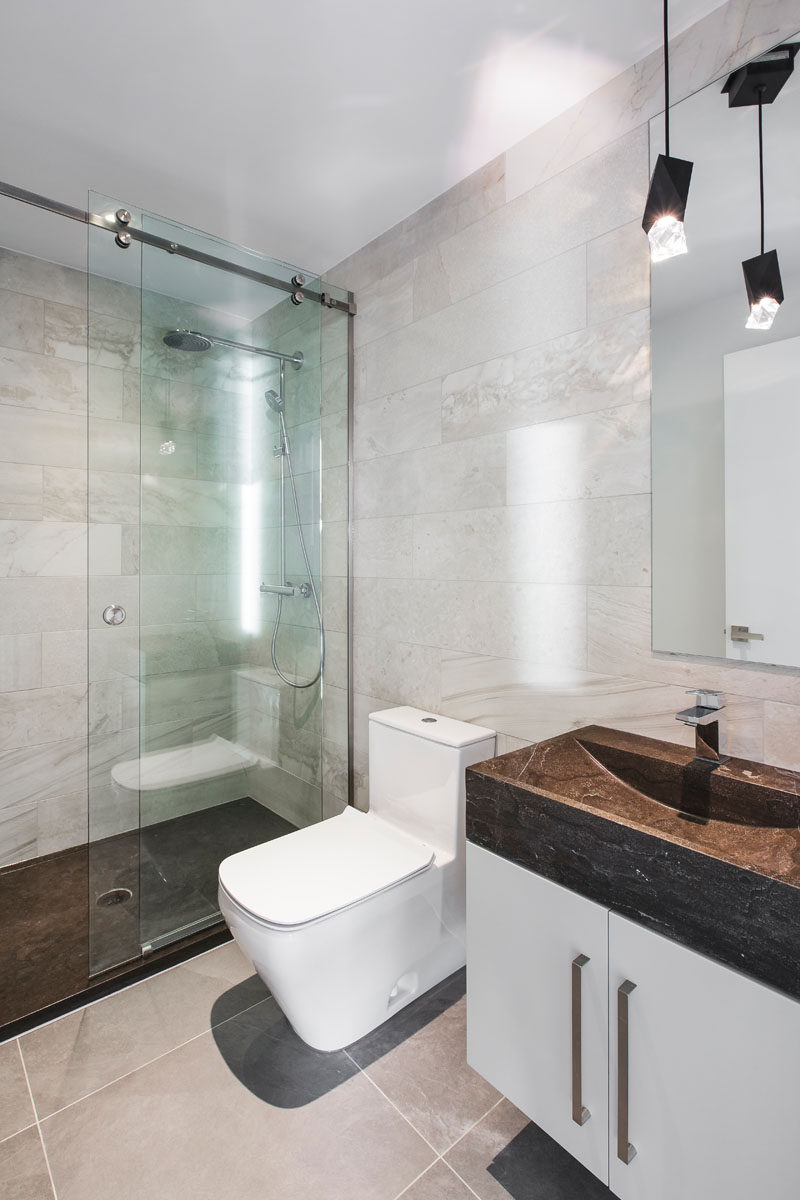 In this modern guest bathroom, the dark flooring in the shower matches the stone vanity.