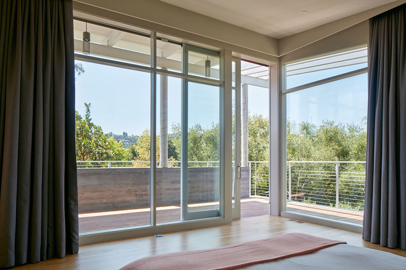 This master bedroom has large floor-to-ceiling windows, and sliding doors provide access to a covered porch.