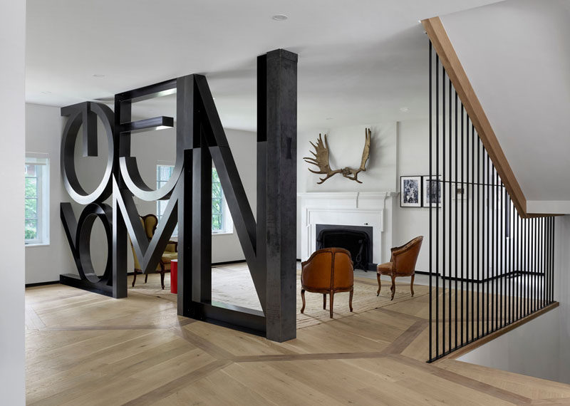 In this formal living room in a renovated heritage house, a word art installation by Commute Design takes the place of a wall. The home owners use this heritage part of the home to display their collection of vintage chairs.