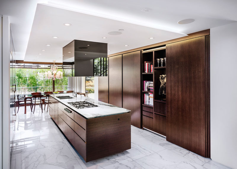 In this kitchen, white marble surfaces have been combined with dark wood cabinetry to create a warm modern appearance.