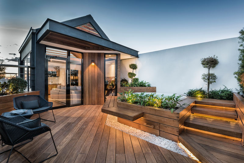 This modern rooftop terrace features hidden lighting that creates a calming ambience, built-in bench seating, and a spa that's surrounded by plants. The plants that are used on the deck also provide an element of privacy to the area.