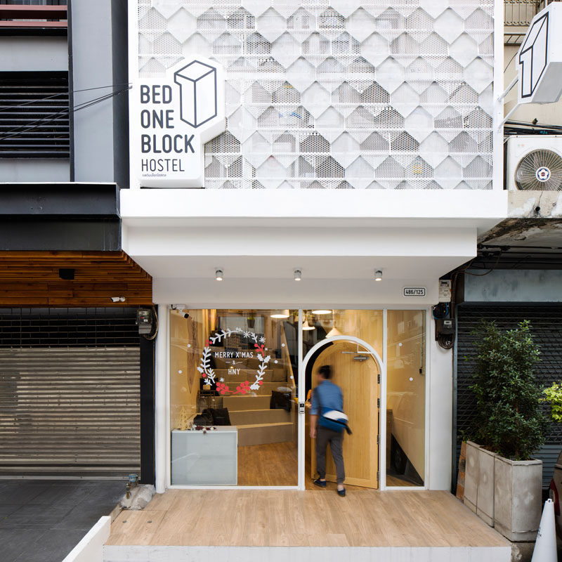 This modern hostel in Bangkok has a welcoming entrance with a wood door surrounded by windows letting you see inside, which is a strong contrast to the surrounding buildings with their metal doors and bars.