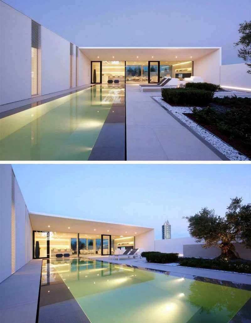 15 Single Story Modern Houses | The touches of black on the exterior of this all white single level house create a dramatic contrast that's made even more dramatic with the help of the lights in the pool and near the fence.