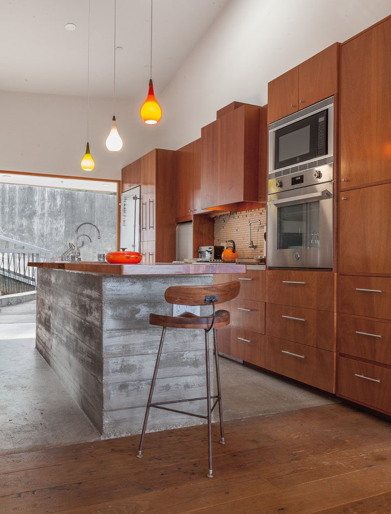 Raw concrete has been paired with wooden cabinetry and floors in this contemporary kitchen.